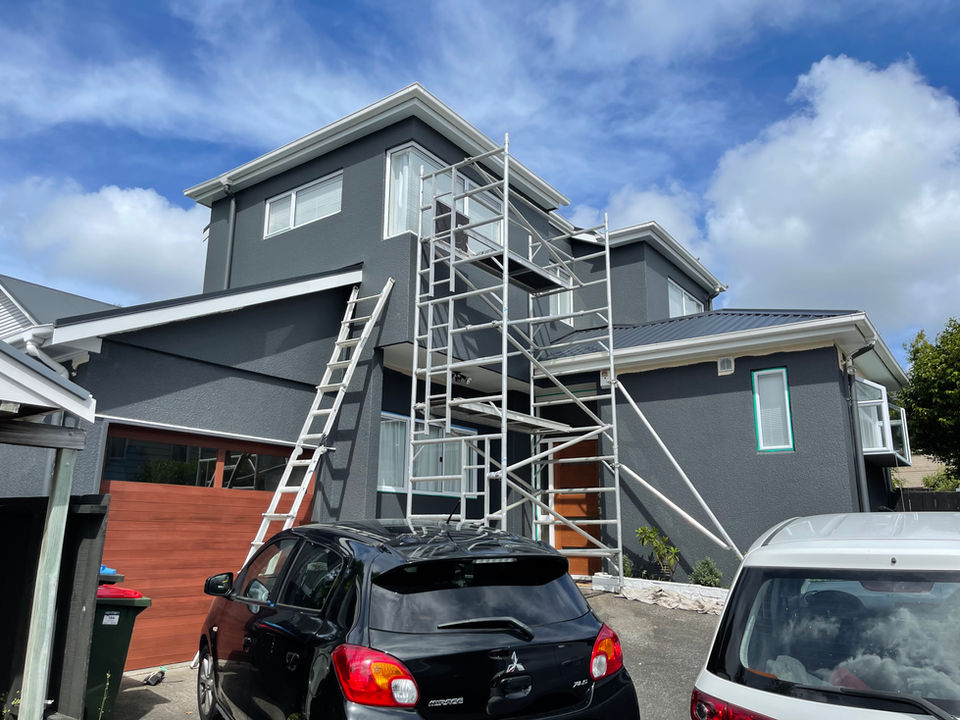 House exterior mid-repaint with scaffold