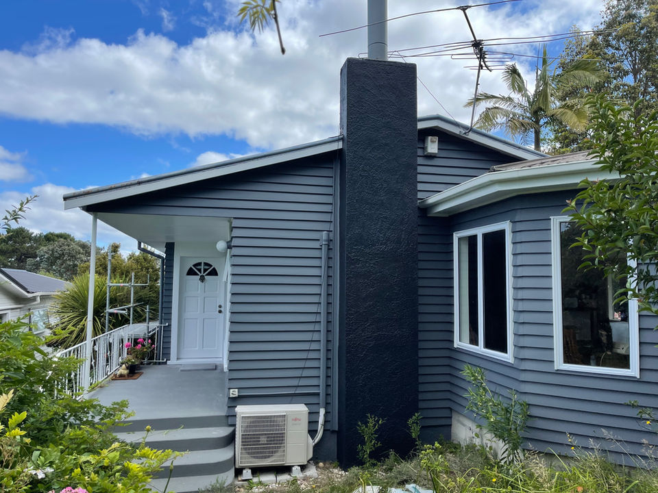 Grey home with dark chimney and tidy garden