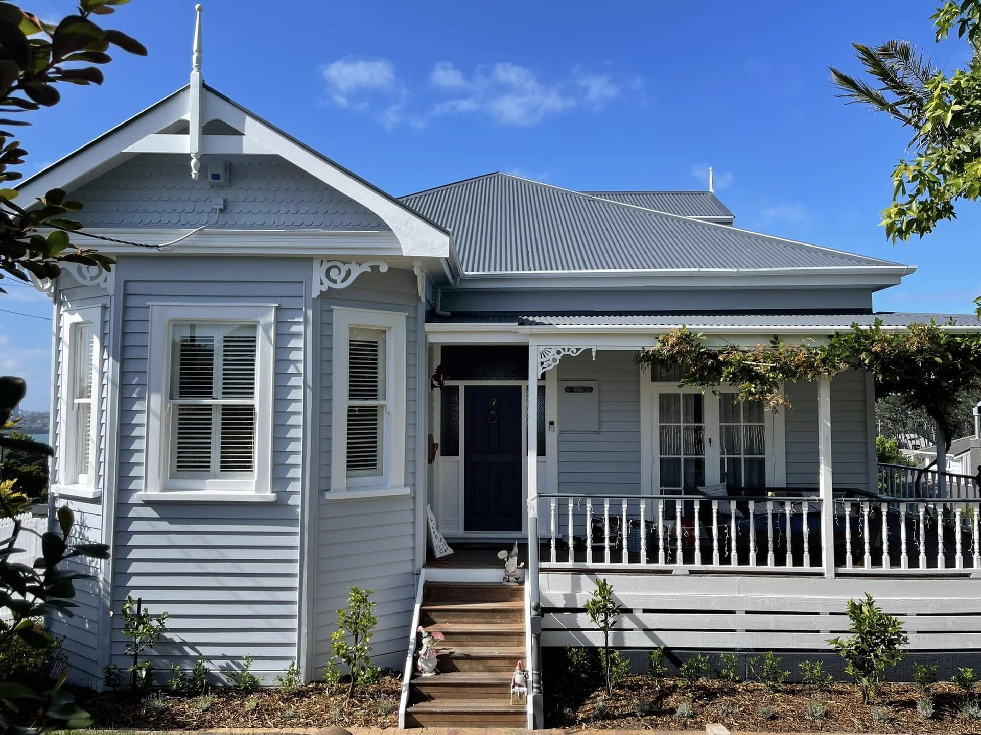 Grey weatherboard villa with veranda, freshly painted